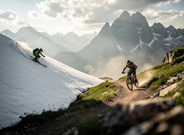 Cinematic wide photo of a mountain sports scene: a skier and a downhill mountain biker in the same atmospheric alpine environment, dramatic winter-to-summer transition, modern gear, clean composition, soft natural light, high detail, realistic, website hero image, shallow depth of field, no text, no logos
